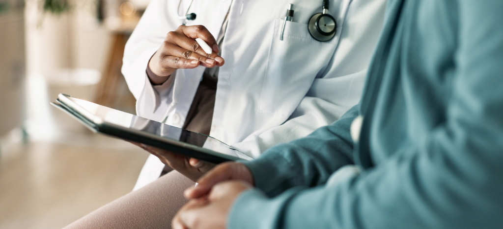 Transparency in infusion centers - A female doctor holding a tablet device while explaining treatment costs to her patient.