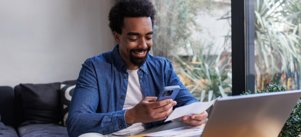 Improving billing for medical practices - A male patient at home paying his medical bills through his smartphone and laptop.