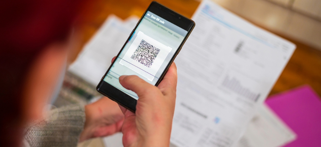 Payment options - A woman at home using her smartphone to scan a QR code printed on her medical bill.