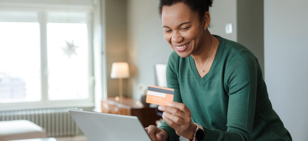 A woman at home holding her credit card while paying her medical bills online.