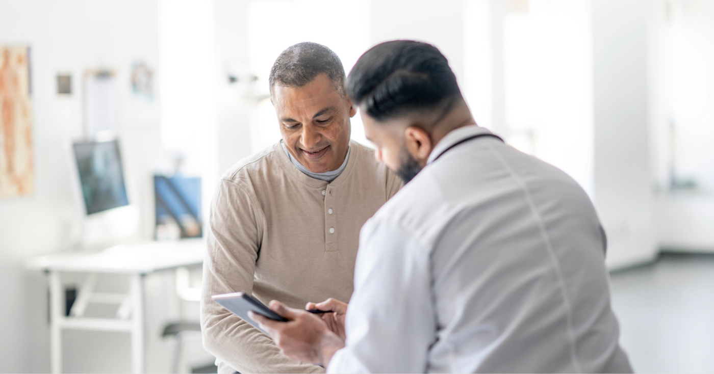 Deductible reset - A male doctor using a tablet device to explain financial options to his male patient.