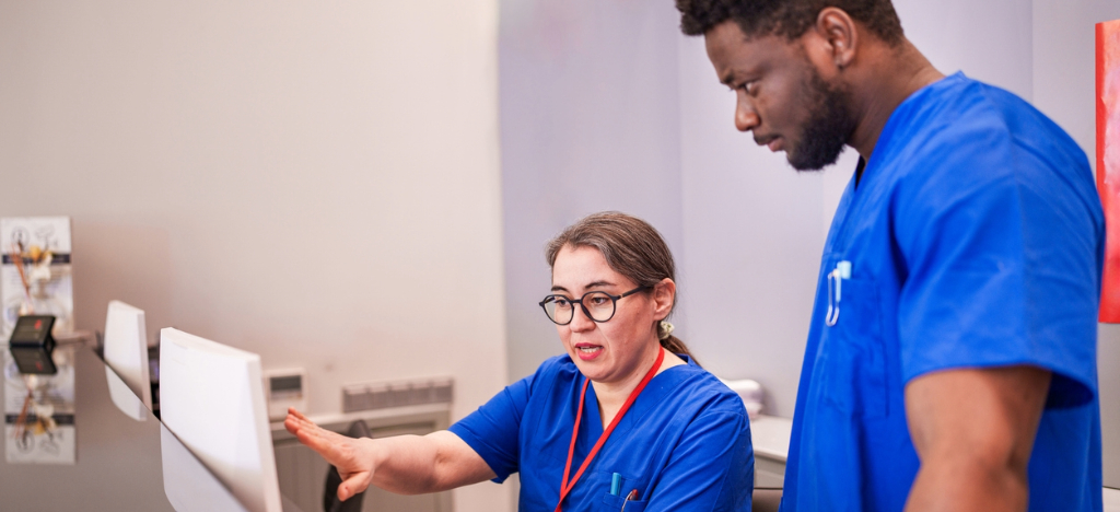 Leveraging payment reminders - A female hospital staff member teaching her colleague on how to use their medical billing software.