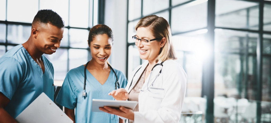 Stop chasing payments - A female doctor using a tablet device to show their medical billing software to her hospital staff.