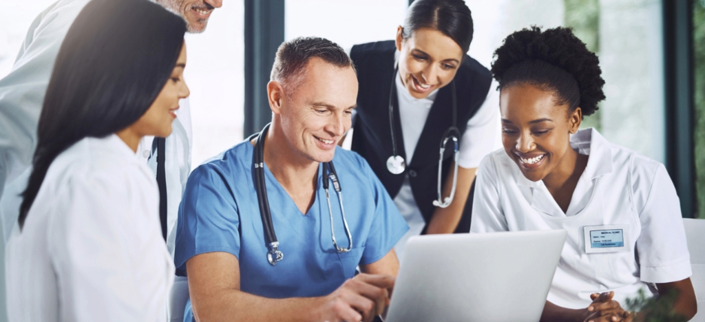 Using medical billing systems - A group of medical professionals looking at a laptop showing modern medical billing software.