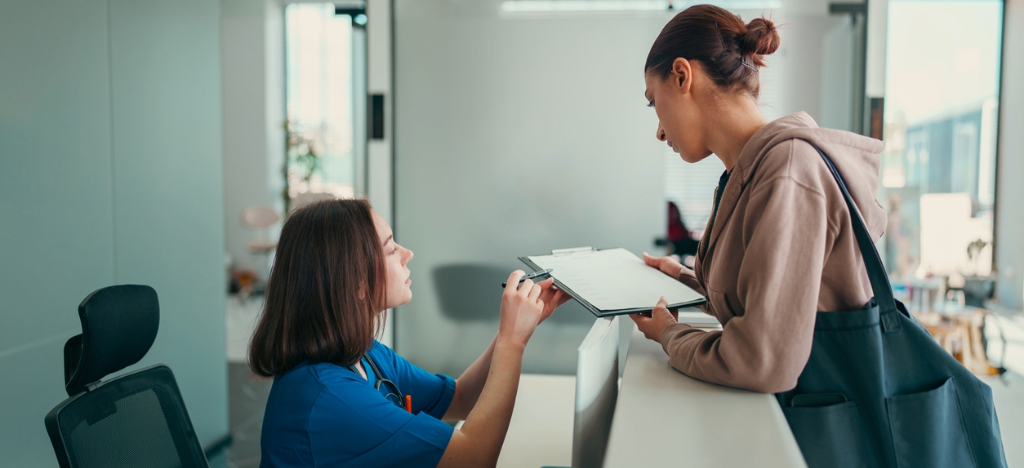 Medical billing software systems - A female nurse showing a printed copy of a medical bill to a female patient.