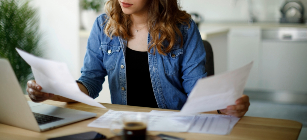 Safeguarding financial health - A woman at home reviewing her mailed medical bills.