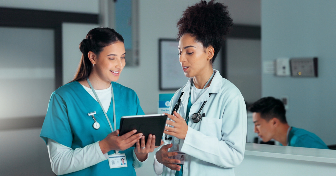 Two female doctors looking at their practice’s billing software using a tablet device.