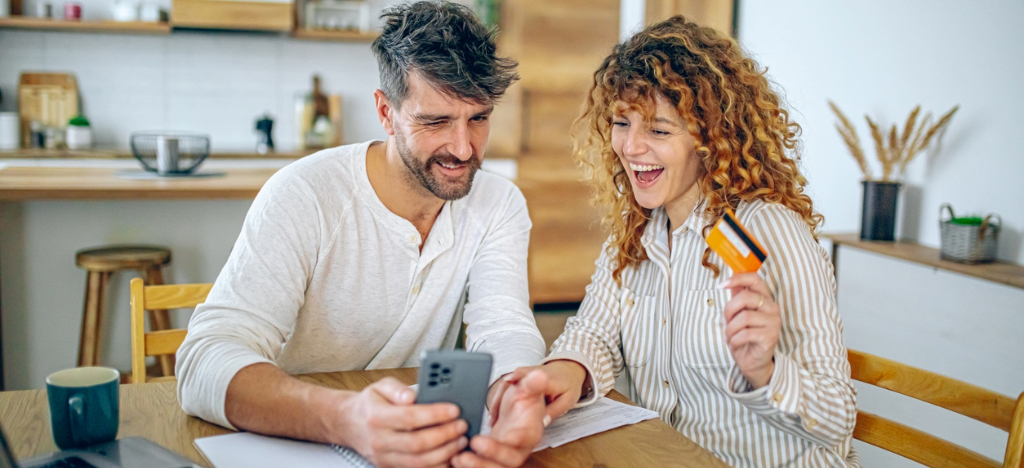 Automatic payment programs for patients - A couple at home booking their medical appointment online using a smartphone.