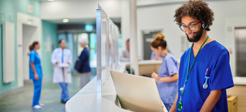 Stop chasing payments - A male hospital staff member checking patient bills on a computer.
