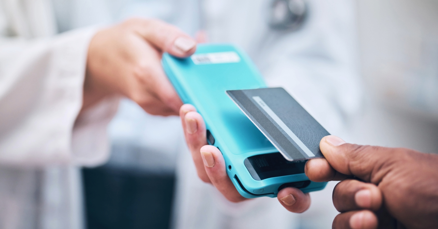 In-office payment for medical practices - A man paying his medical bill by tapping his credit card on an EMV reader.